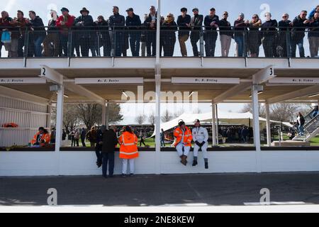 Zuschauer stehen auf dem Dach der Pit Lane und Marshals sitzen auf der Pit Lane Wall, 79. Mitgliederversammlung, Goodwood Motor Racing Circuit, Großbritannien Stockfoto