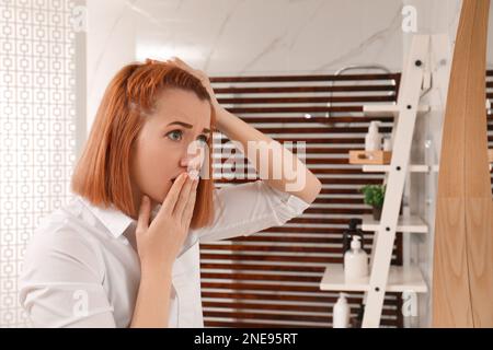 Emotionale Frau mit Glatze in der Nähe des Spiegels zu Hause Stockfoto