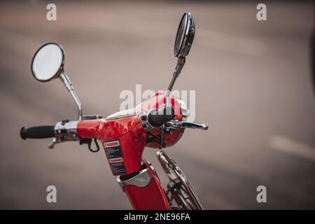 Eine Nahaufnahme der Griffe und Spiegel eines roten Motorrollers. Stockfoto