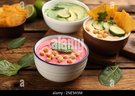 Schüssel mit köstlichem rosa Hummus mit Spinat auf einem Holztisch Stockfoto