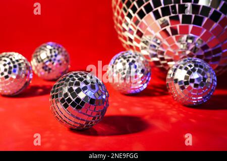 Wunderschöne glänzende Discobälle auf rotem Hintergrund, Nahaufnahme Stockfoto