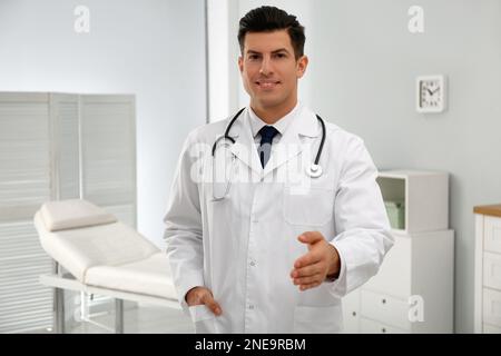 Glücklicher männlicher Arzt bietet Handschlag in der Klinik an Stockfoto