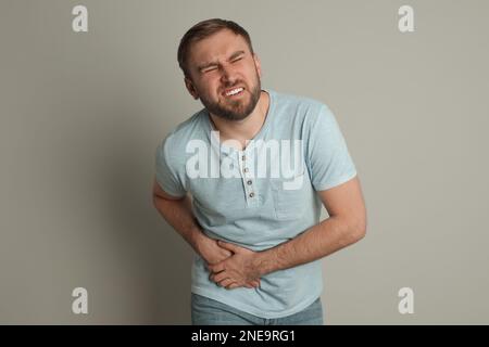 Mann mit akuter Appendizitis auf hellgrauem Hintergrund Stockfoto