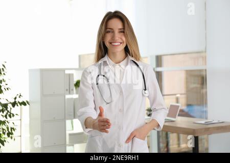 Glückliche Ärztin, die in der Klinik einen Händedruck anbietet Stockfoto