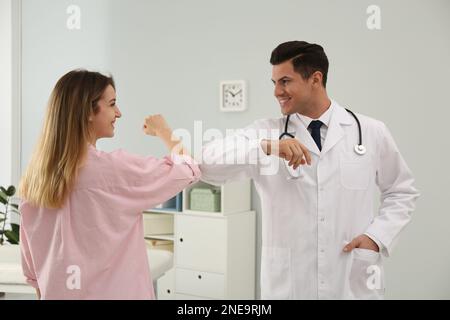 Arzt und Patient mit Ellenbogenbeulung statt Handschlag in der Klinik. Neuer Gruß während der COVID-19-Pandemie Stockfoto