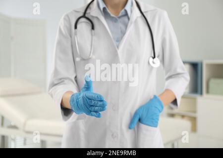Weibliche Ärztin in Handschuhen, die drinnen Handschlag anbietet, Nahaufnahme Stockfoto