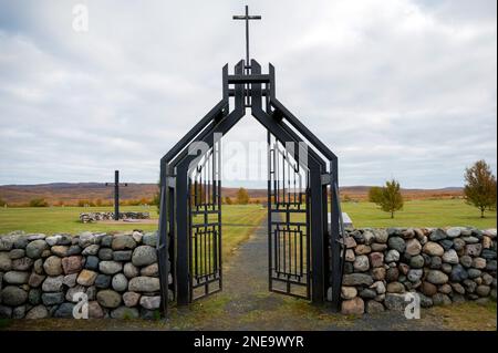 Bogen des Eingangs zum deutschen Militärfriedhof an der Siedlung Pechenga, Region Murmansk. Schwarze Eisentore zum Friedhof. Stockfoto