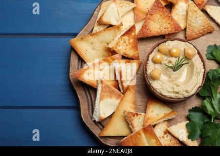 Köstliche Pita-Chips mit Hummus auf blauem Holztisch, Blick von oben Stockfoto