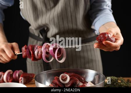 Eine Frau, die mariniertes Fleisch auf einem Spieß am Tisch aufhängt, Nahaufnahme Stockfoto