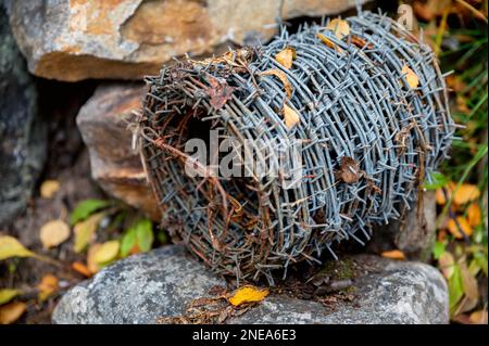 Ansicht einer rostigen Spirale von altem Stacheldraht auf einem Stein, Nahaufnahme. Stockfoto