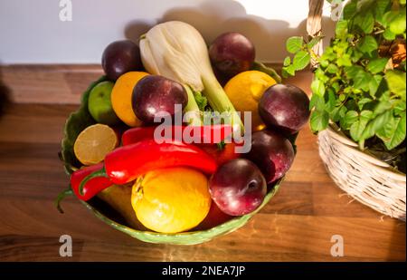 Obstschale mit Fenchel, Pflaumen, roten Chilis und Zitronen Stockfoto