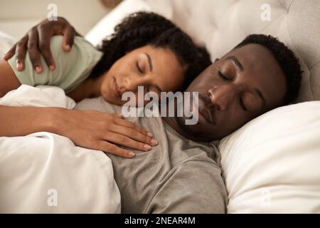 Ein junges, multirassisches Paar, das morgens im Bett schläft Stockfoto