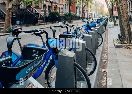 New York, USA - 22. November 2022: Nahaufnahme einer Reihe von Citi Bikes, die an den Docks in einer Straße in Manhattan, New York, geparkt sind. Citi Bike ist ein Privatfahrzeug Stockfoto