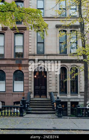 New York, USA - 21. November 2022: Außenansicht eines traditionellen Stadthauses mit einer treppe in West Village, einer bezaubernden Gegend von Manhattan, die für ihre Geschäfte berühmt ist Stockfoto