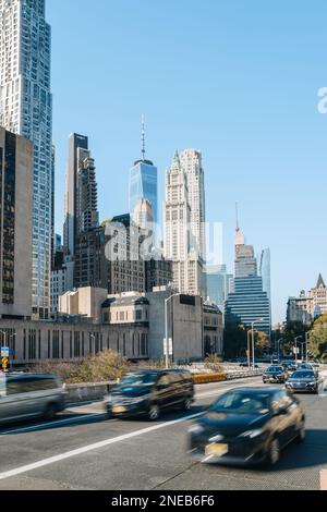 New York, USA - 22. November 2022: Wolkenkratzer im Financial District von der Brooklyn Bridge, New York, Autos, die vorne fahren, Bewegungsunschärfe. Stockfoto