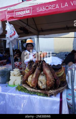 Eine Dame in traditioneller Kleidung, die geröstetes Meerschweinchen (Cuy) verkauft, eine traditionelle Delikatesse in Peru Stockfoto