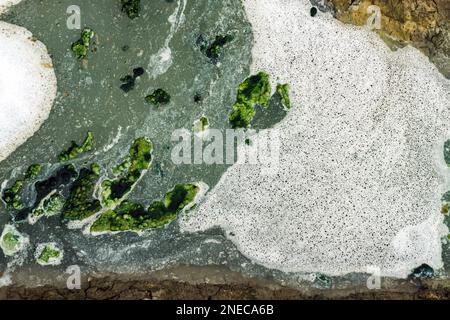 Ansicht von oben: Abwasser mit Luftblasen und Moos, das durch einen gerissenen Graben fließt. Sauerstoffblase in der Schmutzwasseraufbereitung in einem wassergefüllten Graben Stockfoto