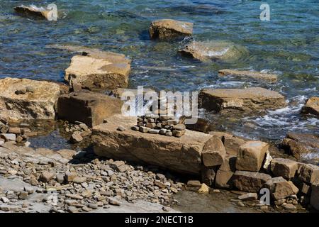 Pyramide aus Kieselsteinen am felsigen Ufer der Adria in Piran, Slowenien. Stockfoto