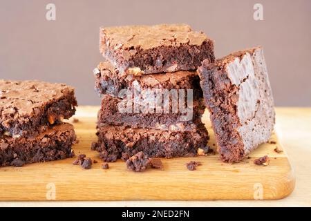 Eine Charge frisch gebackener dreifach-Schokoladen-Brownies auf einem hölzernen Servierbrett. Die Brownies sind noch warm und klebrig. Ein Genuss Stockfoto