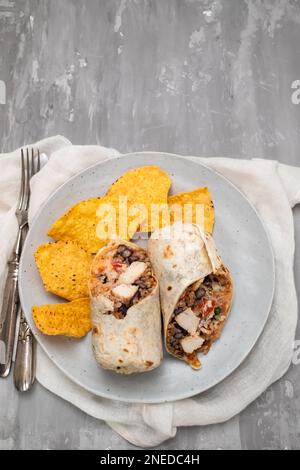 Mexikanischer Rindfleischburrito auf einem kleinen Teller mit Chips Nachos auf dem Teller Stockfoto