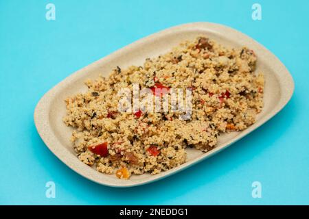 Couscous mit Gemüse in einem Gericht auf blauem Papier Stockfoto