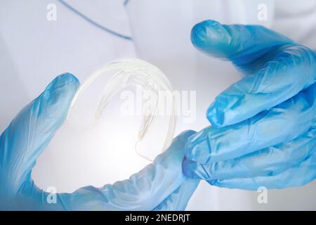 Zahnärztliche Versorgung. Abnehmbare durchsichtige Streben in der Arzthand, kieferorthopädischer Silikontrainer. Ärzte Hände halten Silikon-Mundschutz Stockfoto