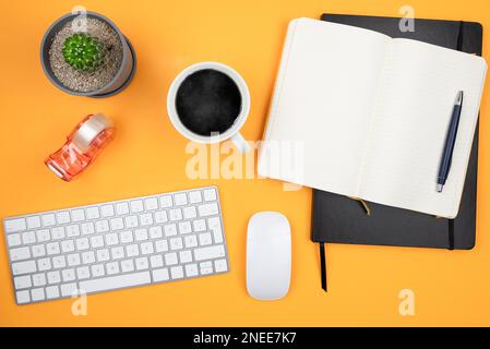 Direkt über dem Bild des Büro-Arbeitsplatz mit Computer-Tastatur, Maus, Kaffeetasse, Notizblock und Topfpflanze, Home-Office und Arbeiten von zu Hause Stockfoto