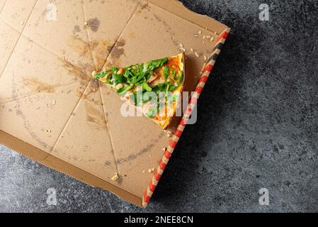 Oben Ansicht der letzten Scheibe Pizza in Pappkarton auf Steinküchentisch Stockfoto