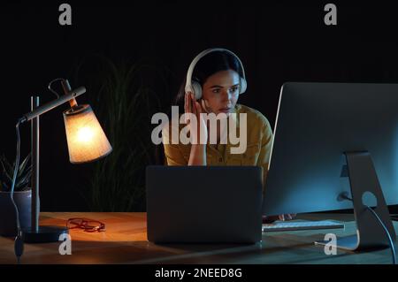 Programmierer mit Kopfhörern, der nachts im Büro arbeitet Stockfoto