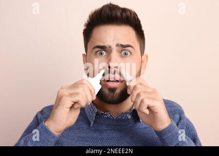 Mann mit Nasensprays auf beigefarbenem Hintergrund Stockfoto