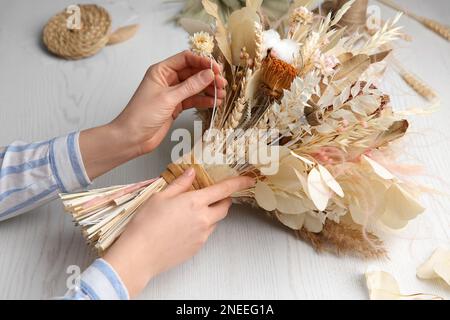 Florist, der einen wunderschönen Strauß getrockneter Blumen am weißen Tisch macht, Nahaufnahme Stockfoto