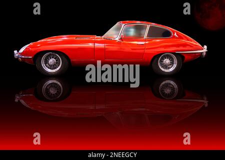 Jaguar E Type in Seitenansicht, rot lackierter klassischer Sportwagen aus England, reflektiert auf dem Boden, Essen, Deutschland, 5. Dezember 2022 Stockfoto