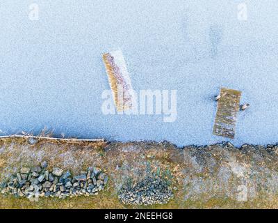 Luftaufnahme des Ufers eines gefrorenen Sees mit eisigen Piers, Terény, Ungarn Stockfoto