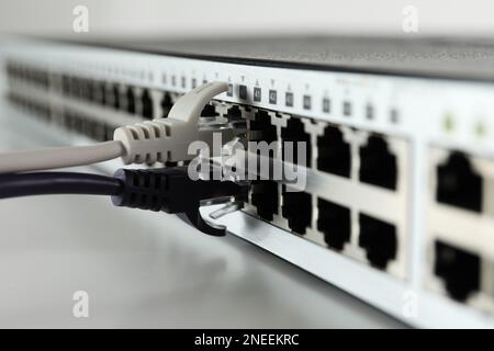 Nahaufnahme des Netzwerk-Switches mit Kabeln auf hellem Hintergrund. Internetverbindung Stockfoto