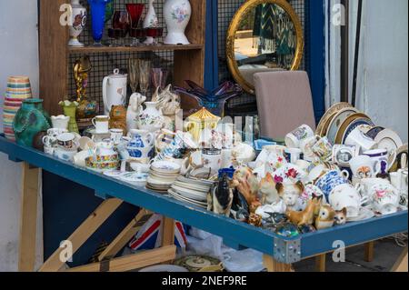 Eine Auswahl an alten Ornamenten, Porzellan, Keramik und Bric-a-brac auf einem Tisch vor einem Antiquitätenladen in der Portobello Road. Nach London. Stockfoto