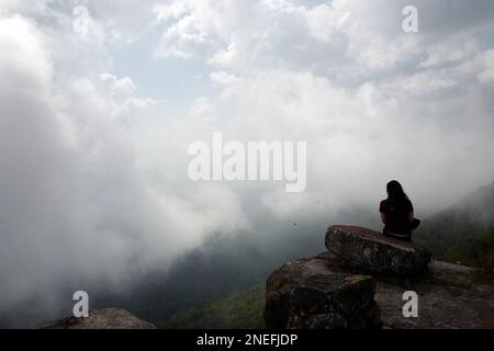 Ein Mädchen blickt über die Wolken am Bokor Mountain in Kambodscha. Stockfoto
