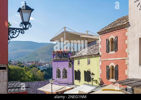 Touristen auf der Terrasse von Restaurants und pastellfarbenen Häusern in der Altstadt von Mostar, Kanton Herzegovina-Neretva, Bosnien und Herzegowina Stockfoto