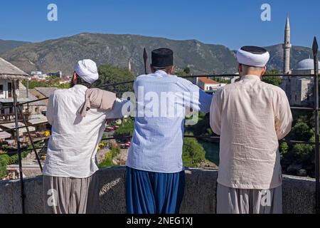 Drei muslimische Männer auf der Stari Most, osmanische Brücke aus dem 16. Jahrhundert in der Stadt Mostar, Kanton Herzegowina-Neretva, Bosnien und Herzegowina Stockfoto