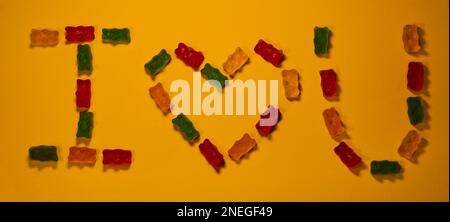 Konzept des Valentinstages. Draufsicht. Flatlay-Grußkarte. Bunte, süße Marmeladen in Form von Bären, mit Buchstaben mit Inschrift, die ich liebe, gefüttert Stockfoto