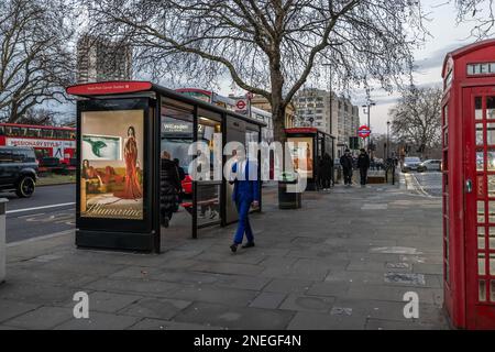 An einem Winterabend im Zentrum von London, England, geht ein Geschäftsmann mit einem leuchtend blauen Anzug in Richtung Knightsbridge über die Hyde Park Corner Stockfoto