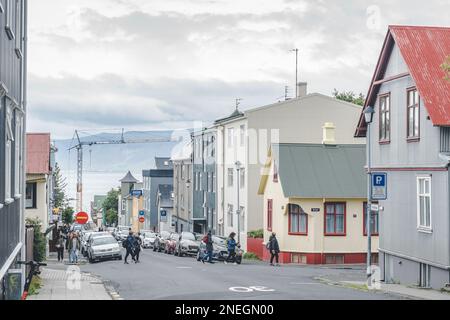 Reykjavik, Island - Juli 17 2022: Straße mit Häusern und Restaurants mit Blick auf die Berge und das Meer Stockfoto