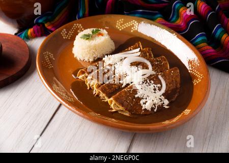 Hühnerenmoladas. Auch bekannt als Mole poblano enchiladas, sind sie ein typisches mexikanisches Gericht, das in Mexiko und dem Rest der Welt sehr beliebt ist. Stockfoto