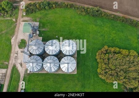 Landwirtschaftliche Silos auf dem Hof im Herbst, Nahaufnahme der Drohne. Industriekörner, Aufzugtrockner, Gebäudeaußenseite, Lagerung und Trocknung von Getreide Stockfoto