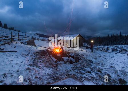 Ein Feuer brennt in der Nähe der alten Hirtenhütte in den Karpaten in den Bergen, abends in der Natur Stockfoto
