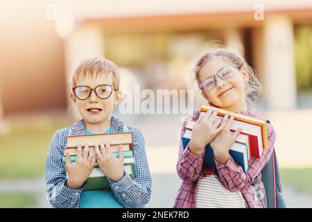 Mädchen und Junge in Brille stehen mit Büchern in den Händen. Stockfoto