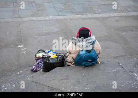 Eine Frau mit ihren Sachen, die auf den Stufen des Shaftesbury Memorial Fountain in London, England, sitzt Stockfoto