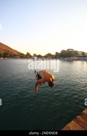 Bodrum, Türkei. 26. August 2015: Der junge Mann hat Spaß, wenn er am Karaincir-Strand des beliebten Urlaubsziels Bodrum ins Meer springt. Stockfoto