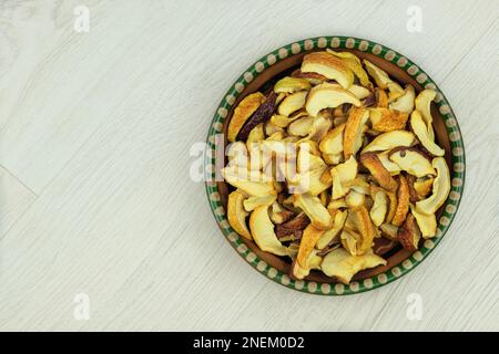 Getrocknete Äpfel auf einem Tonteller auf Holzhintergrund. Vegetarische Bio-Lebensmittel. Draufsicht. Stockfoto