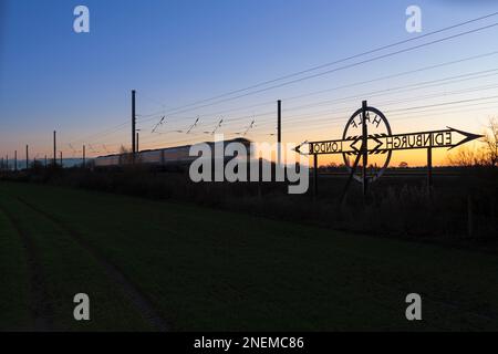 Newton on Ouse (North of York) London nach Edinburgh auf halbem Weg Schild an der Ostküste Hauptlinie bei Sonnenuntergang mit einem vorbeifahrenden TransPennine Express Zug Stockfoto