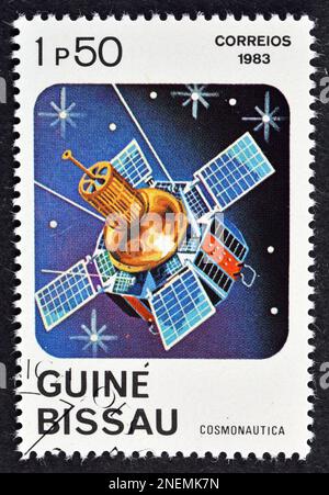 Abgesagte Briefmarke, gedruckt von Guinea-Bissau, auf der Satellit, Kosmonautiktag, um 1983. Stockfoto